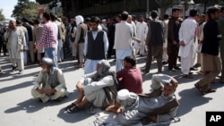 Afghan protesters sit on the ground to block one of the main Kabul streets during a demonstration against the government, in Kabul, Afghanistan, Oct. 7, 2015. 
