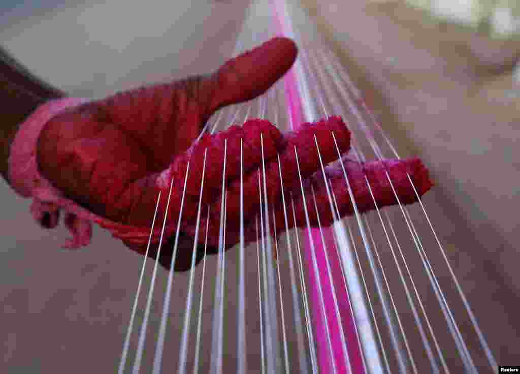 A worker applies color to strings which will be used to fly kites, by a roadside in Ahmedabad, India.