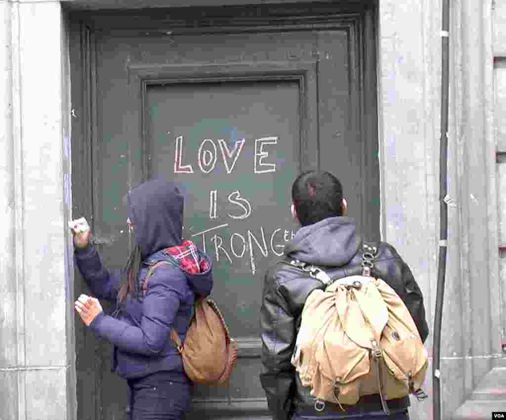 People scrawl messages on a doorway at the Place de la Bourse in downtown Brussels in response to the terrorist attacks that left dozens of people dead, March 23, 2016. (L. Bryant/VOA)