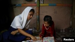 Yasmin, a Rohingya girl who was expelled from Leda High School for being a Rohingya, helps her younger sister to study in Leda camp in Teknaf, Bangladesh, March 5, 2019. REUTERS/Mohammad Ponir Hossain