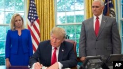 President Donald Trump signs an executive order to keep families together at the border, but says that the 'zero-tolerance' prosecution policy will continue, during an event in the Oval Office of the White House in Washington.