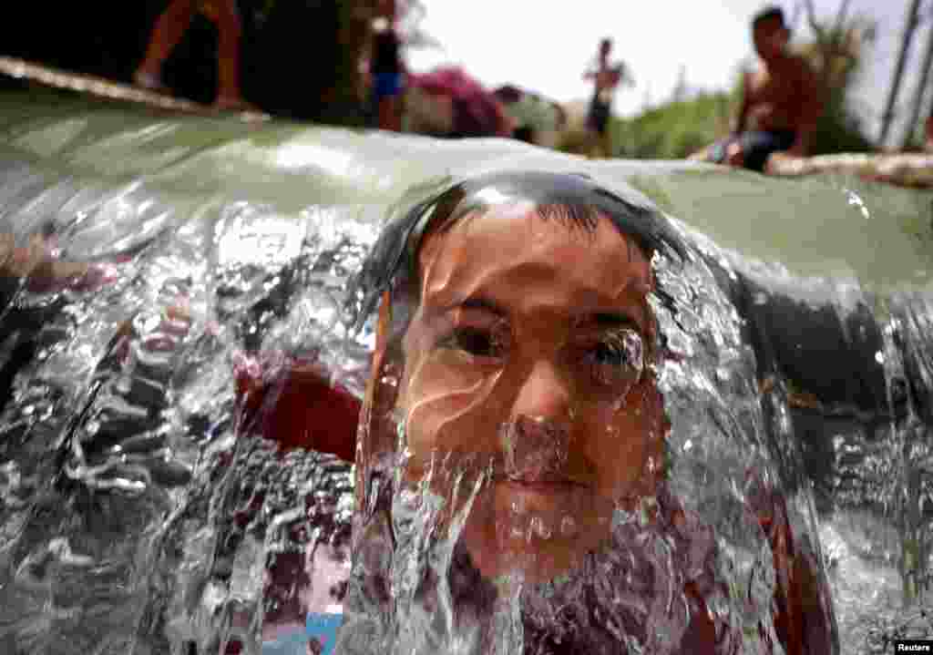 A Palestinian boy dips in a natural spring to cool off during a heat wave near Jericho in the Israeli-occupied West Bank.