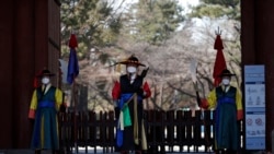 Guardias con uniformes tradicionales y mascarillas ante la entrada del palacio Deoksu en el centro de Seúl, Corea del Sur, el domingo 23 de febrero de 2020. (AP Foto/Lee Jin-man)