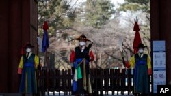 Guardias con uniformes tradicionales y mascarillas ante la entrada del palacio Deoksu en el centro de Seúl, Corea del Sur, el domingo 23 de febrero de 2020. (AP Foto/Lee Jin-man)
