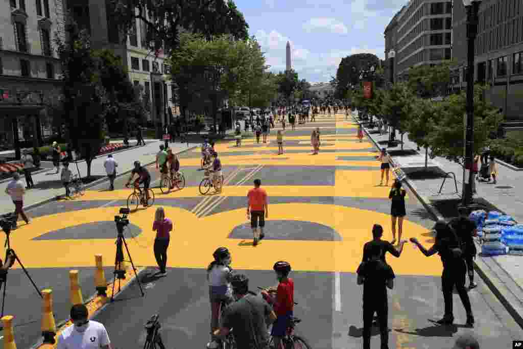 With the Washington Monument in the background, people walk on the street leading to the White House after the words &quot;Black Lives Matter&quot; were painted on it by city workers and activists in Washington, D.C. (AP Photo/Manuel Balce Ceneta)