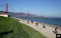 FILE - In this Nov. 25, 2014, photo, bicyclists ride past Crissy Field near the Golden Gate Bridge in San Francisco. Federal authorities have approved a politically conservative group's application to hold a rally at Crissy Field in San Francisco on Aug. 26, 2017.