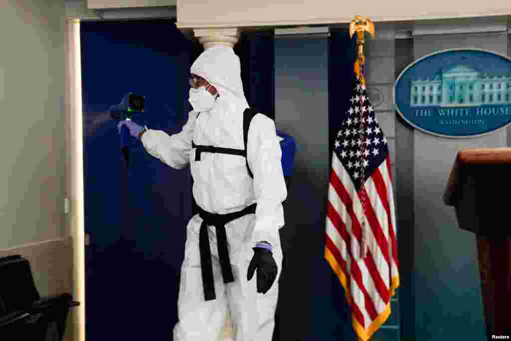 A member of the White House cleaning staff sprays the press briefing room in Washington, Oct. 5, 2020.