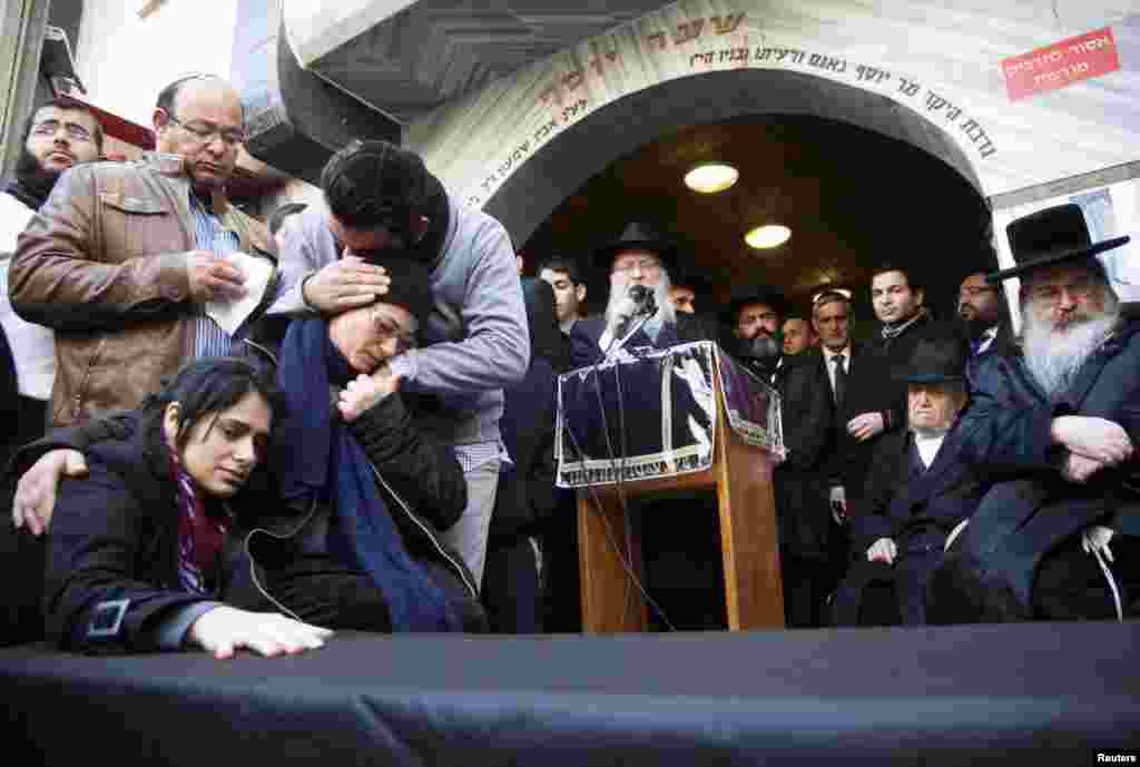 The mother (2nd left) and sister (left) of Yoav Hattab, killed in an attack on a Paris grocery on Friday, mourn beside a symbolic coffin during a procession before his funeral in Bnei Brak, near Tel Aviv, Jan. 13, 2015.