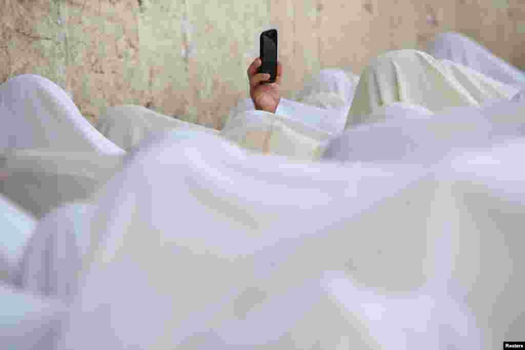 A Jewish worshipper uses his mobile phone to record worshippers who are covered in prayer shawls as they recite the priestly blessing at the Western Wall in Jerusalem's Old City during the Jewish holiday of Sukkot.