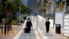 Pria Ultra-Ortodoks Yahudi mengenakan masker, berjalan di trotoar saat diberlakukannya lockdown di tengah meningkatnya kasus Covid-19 di Ashdod, Israel, 24 September 2020. (REUTERS / Amir Cohen)