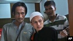 Islamist militant Sigit Indrajit, center, is escorted by plain-clothed police officers after his sentencing proceeding at a district court in Jakarta, Indonesia, Jan. 21, 2014. 