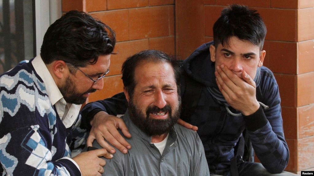FILE - Relatives of a student who was injured during an attack by Taliban gunmen on the Army Public School comfort each other outside Lady Reading Hospital in Peshawar, Dec. 16, 2014.