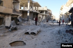 People inspect a damaged site after airstrikes on the rebel-held Sheikh Fares neighborhood of Aleppo, Syria, Oct. 1, 2016.