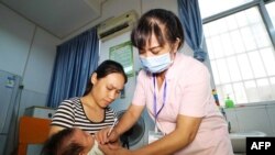 FILE - A child receives a vaccination shot at a hospital in Rongan in China's southern Guangxi region on July 23, 2018. 