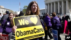 Holding a sign saying "We Love ObamaCare" supporters of health care reform rally in front of the Supreme Court in Washington, Mar. 27, 2012.