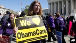 Holding a sign saying "We Love ObamaCare" supporters of health care reform rally in front of the Supreme Court in Washington, Mar. 27, 2012.