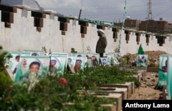 A Shi'ite rebel Houthi stands among the portrait adorned graves of Houthi fighters and supporters who were killed in the ongoing conflict in Yemen, a few hours before the start of a fresh cease-fire, in Sana'a, Yemen, April 10, 2016.