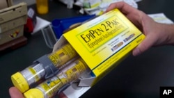 FILE - In this July 8, 2016, file photo, a pharmacist holds a package of EpiPens epinephrine auto-injector, a Mylan product, in Sacramento, Calif. Mylan said it will make available a generic version of its EpiPen, as criticism mounts over the price of its injectable medicine.