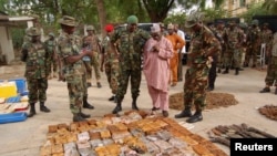 Military officials stand near ammunitions seized from suspected members of Hezbollah after a raid of a building in Kano, Nigeria, May 30, 2013.