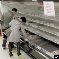 People shop for food from an almost empty shelf at a Tokyo store, March 15, 2011.