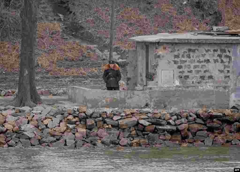 A North Korean soldier stands watch by the Yalu River in the North Korean town of Sinuiju across from the Chinese city of Dandong.