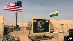 In this photo taken April 16, 2018, a U.S. and Niger flag are raised at the base camp for air forces and other personnel supporting the construction of Niger Air Base 201 in Agadez, Niger. On the edge of the Sahara Desert, the U.S. is building a base for armed drones.