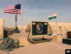FILE - In this photo taken April 16, 2018, a U.S. and Niger flag are raised at the base camp for air forces and other personnel supporting the construction of Niger Air Base 201 in Agadez, Niger.