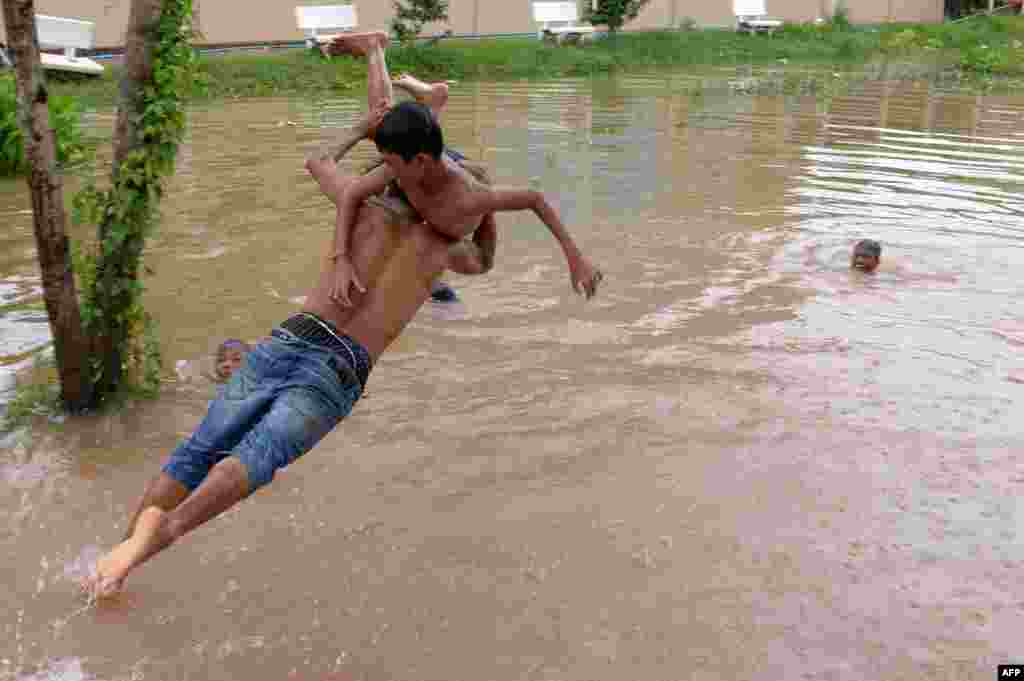 A man carries a boy as he leaps into flood waters on the outskirts of Phnom Penh, Cambodia.