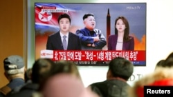 İnsanlar televiziyadan Şimali Koreyanın ballistik raketini sınaqdan keçirməsini izləyir.
