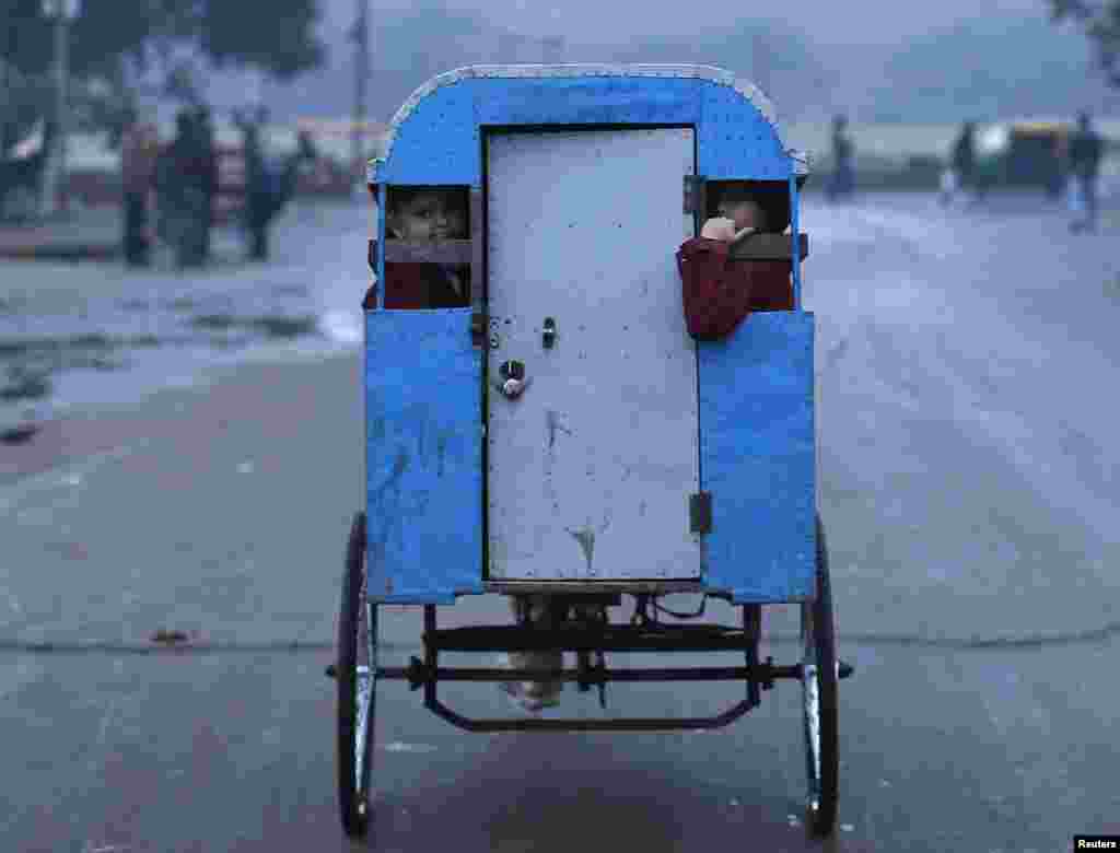 Schoolchildren travel to their school in a rickshaw on a cold morning in the old quarters of Delhi, India.