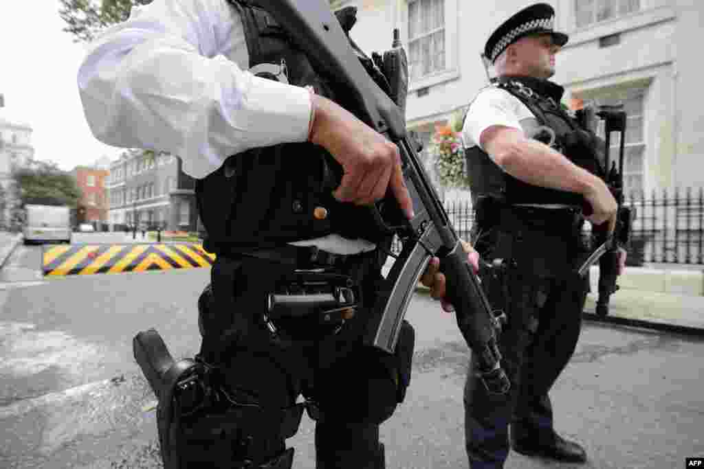 Armed police officers hold guns as they stand on Downing Street, in central London. Britain raised the country&#39;s terror threat risk level to &quot;severe&quot; due to fears over the situation in Iraq and Syria.
