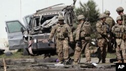 U.S. military forces inspect the site of a suicide attack near a U.S. military camp in Kabul, Afghanistan, Tuesday, Sept. 16, 2014. (AP Photo/Massoud Hossaini)