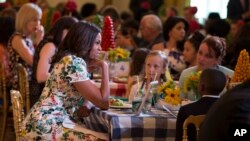 FILE - First Lady Michelle Obama talks with guests during the Kids State Dinner for the 2015 winners of the Healthy Lunchtime Challenge, Washington, July 10, 2015.