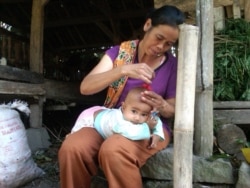 Seorang ibu di Turi, Sleman, Yogyakarta mencukur kepala anaknya di kandang kambing. (Foto:VOA/ Nurhadi)