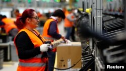 Employees handle packages in the new Amazon logistics center in Dortmund, Germany, Nov. 14, 2017.