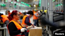 Employees handle packages in the new Amazon logistics center in Dortmund, Germany, Nov. 14, 2017.