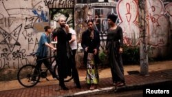 Fernanda, 20, Rodrigo, 26, and Teflon, 19, who are among members of lesbian, gay, bisexual and transgender (LGBT) community, that have been invited to live in a building that the roofless movement has occupied, stand at an entrance of the building, in downtown Sao Paulo, Brazil, Nov. 6, 2016.