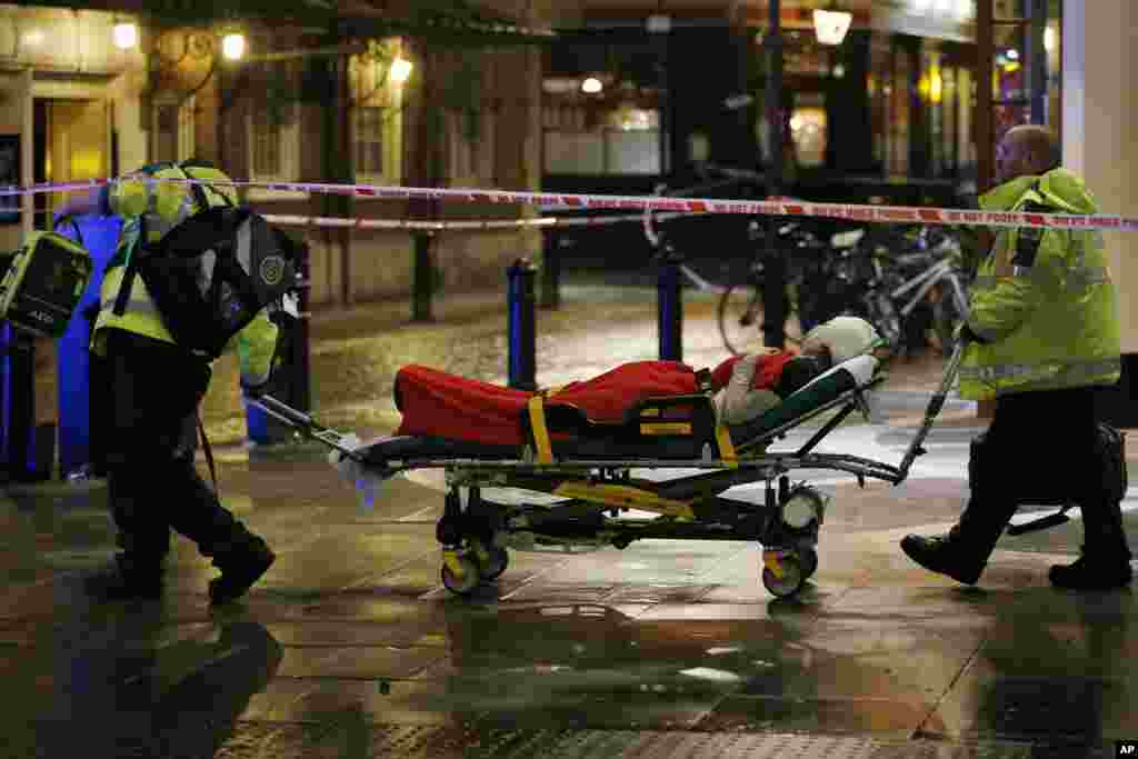 An injured person is wheeled out of a theater used as a makeshift treatment center for the nearby Apollo Theatre after part of its ceiling collapsed, London, Dec. 19, 2013. 