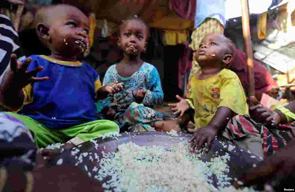 Internally displaced Somali children eat boiled rice outside their family&#39;s makeshift shelter at the Al-cadaala camp in Mogadishu.
