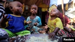 Internally displaced Somali children eat boiled rice outside their family's makeshift shelter at the Al-cadaala camp in Somalia's capital Mogadishu, March 6, 2017.