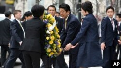 Japanese Prime Minister Shinzo Abe, center right, and his wife Akie, second from right, join aides in placing a wreath at the site of one of the 2013 Boston Marathon bombings Monday, April 27, 2015, in Boston. (AP Photo/Josh Reynolds)