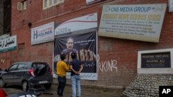 Kashmiri men looks at the poster displaying the picture of slain journalist Shujat Bukhari in Srinagar, Indian controlled Kashmir, July, 4, 2018. Reporters Without Borders has expressed serious concern at ``an alarming deterioration in the working environment of journalists in India’’ and demanded that the government must ensure safety of journalists who are feeling threatened. 