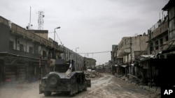 In this Tuesday, May 2, 2017 photo, a humvee of the Iraqi Federal Police drives through an abandoned street in western Mosul, Iraq. 