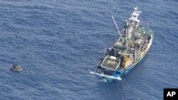 This photo released by the New Zealand Defence Force shows a wooden dinghy, left, carrying seven survivors from a missing ferry and a fishing boat in the Pacific Ocean, Jan. 28, 2018. 