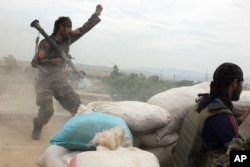 FILE - An Afghan National Army soldier (L) shouts at Taliban fighters, after firing a rocket towards Taliban positions, on the outskirts of Kunduz, northern Afghanistan, April 16, 2016.