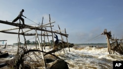 Un homme jonche au sommet d'une structure en bois pour accrocher le filet de pêche traditionnel de Wagenia parlant la langue kilokele, à Kisangani, RDC, 19 avril 2004.