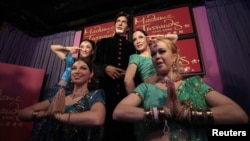 Models pose next to a wax figure of Bollywood icon Amitabh Bachchan.