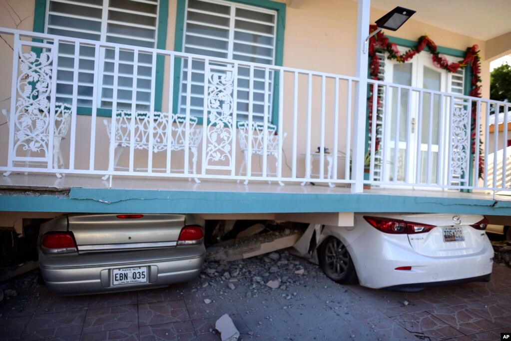 Unos automóviles aparecen aplastados debajo de una casa que se derrumbó después de un terremoto en Guánica, Puerto Rico, el lunes 6 de enero de 2020.