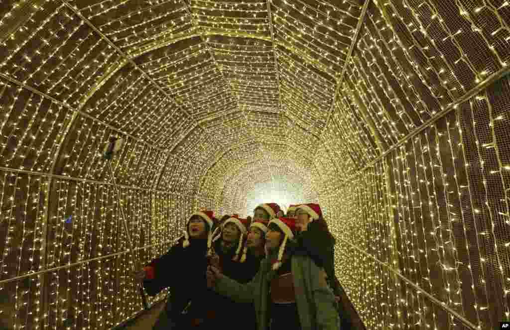 Para pengunjung berfoto selfie di terowongan yang dihiasi cahaya untuk menyambut Natal di Gapyeong, Korea Selatan.