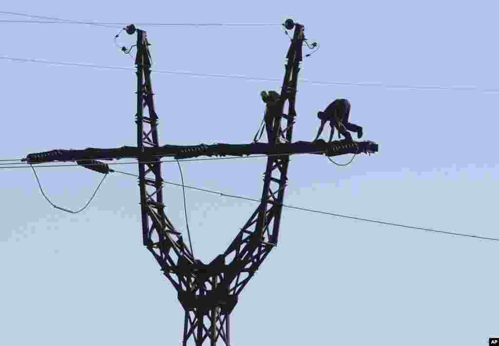 Workers repair an electricity power line damaged during shelling near a power station outside the city of Slovyansk, Donetsk Region, eastern Ukraine.